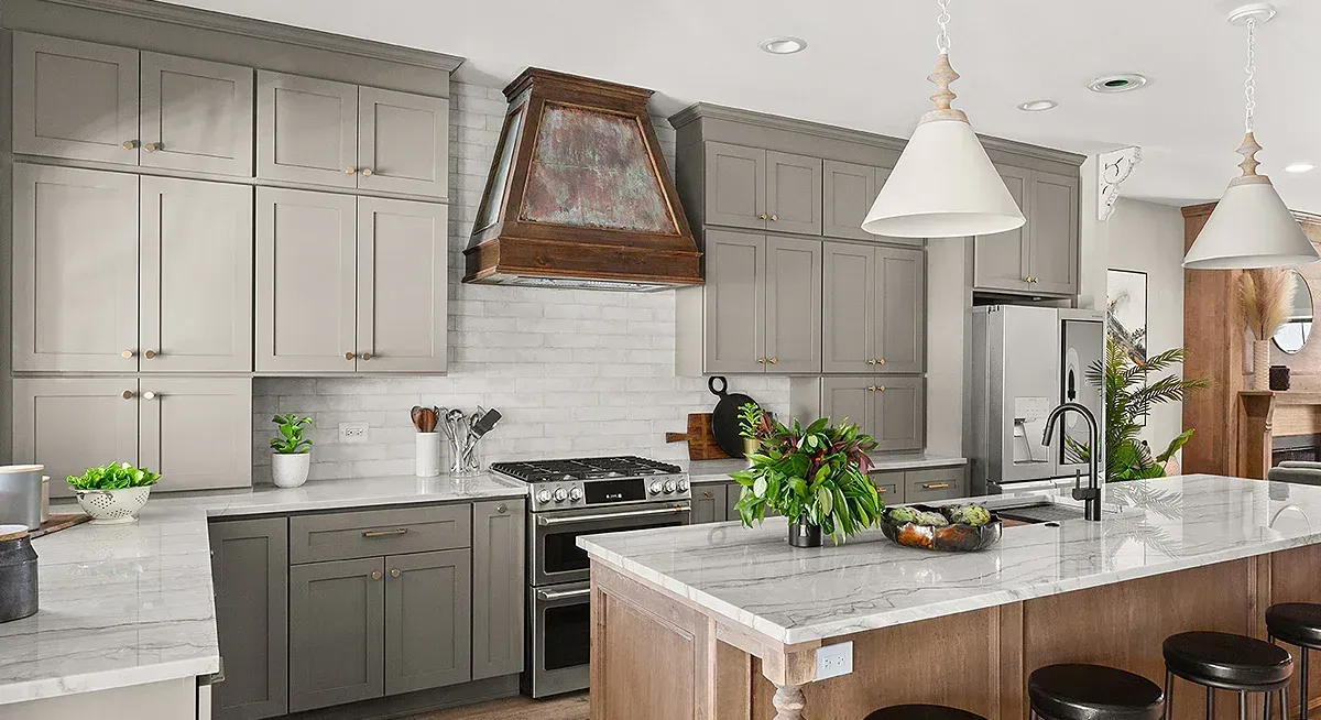 A kitchen with gray cabinets , white counter tops , and a large island.