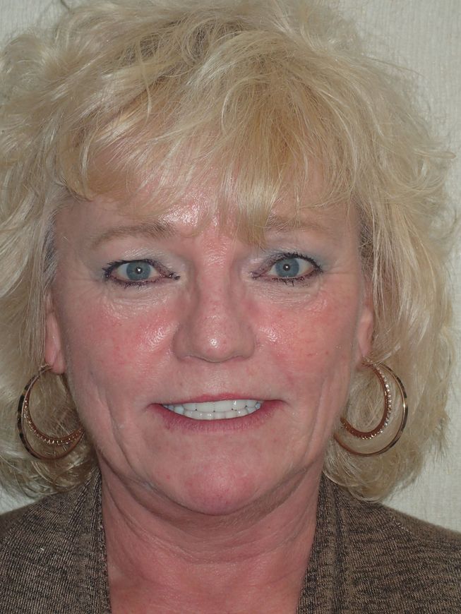 A woman with blonde hair and hoop earrings is smiling for the camera.