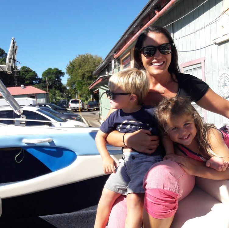 Mother and two children smiling while sitting in a yacht