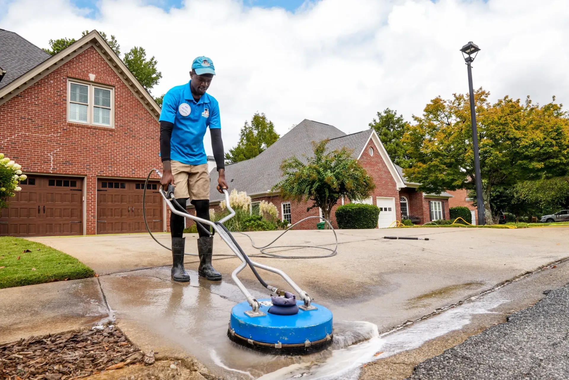 Man pressure washing a brick wall outdoors.