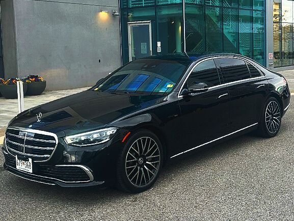 A black mercedes benz s class is parked in front of a building.