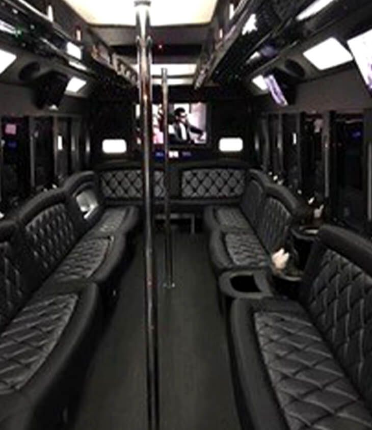 The inside of a bus with black leather seats and a television.