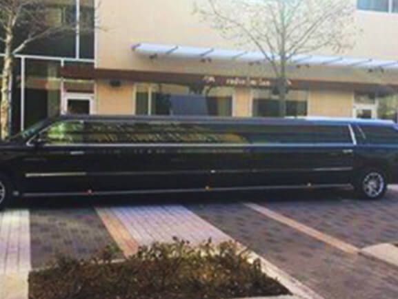 A black limousine is parked in front of a building.