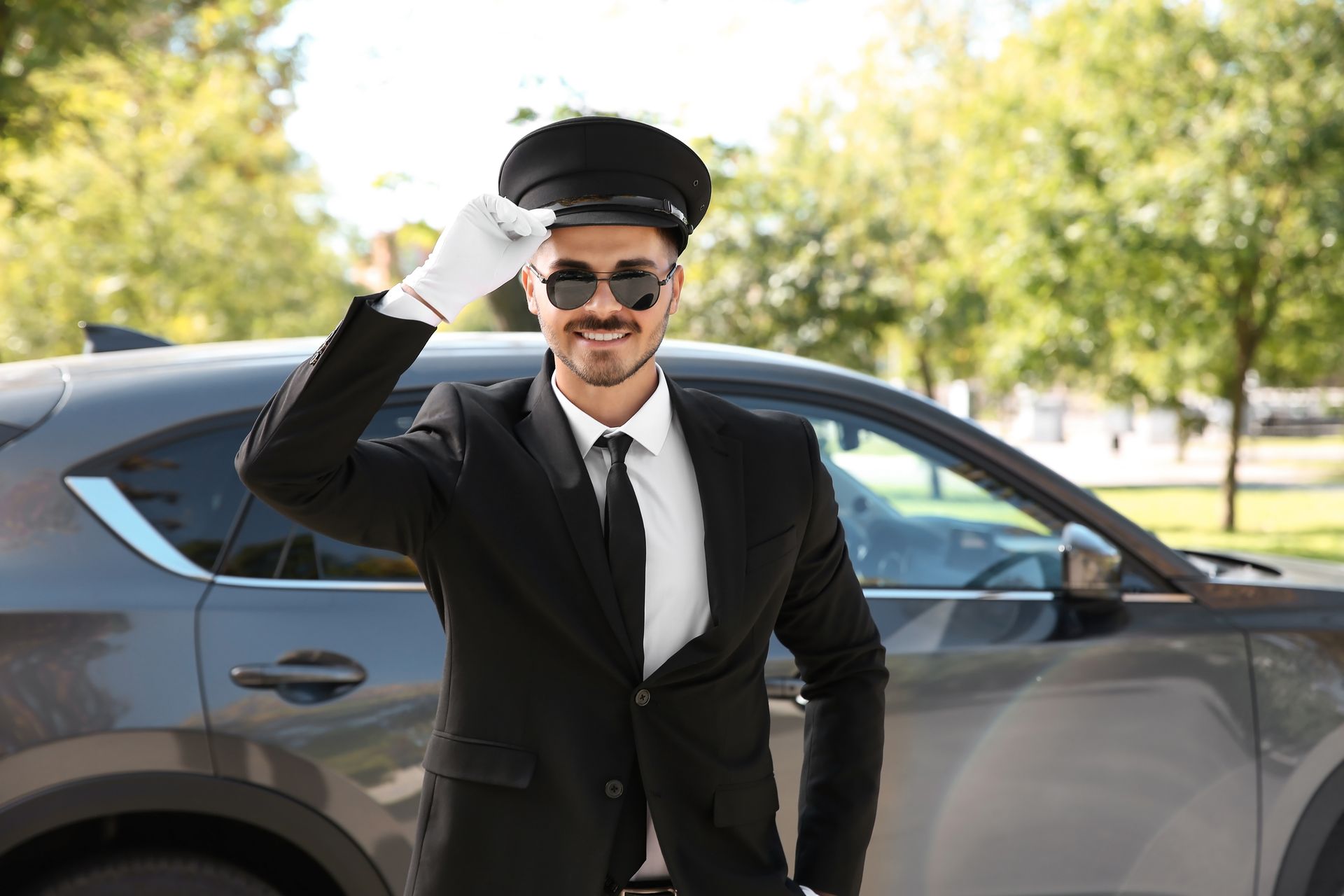 A man in a suit and tie is standing next to a car.