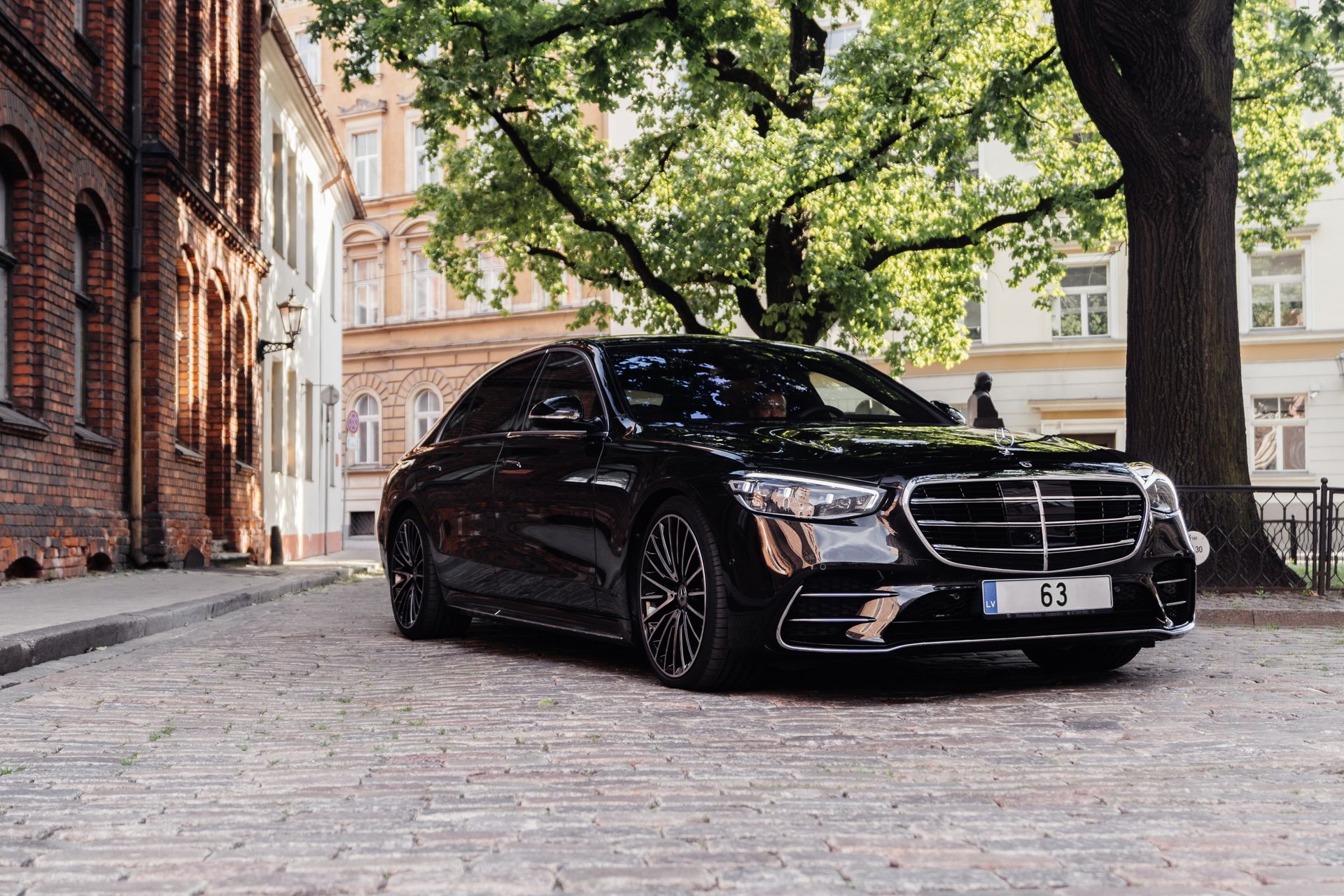 A black mercedes benz s class is parked on a cobblestone street.