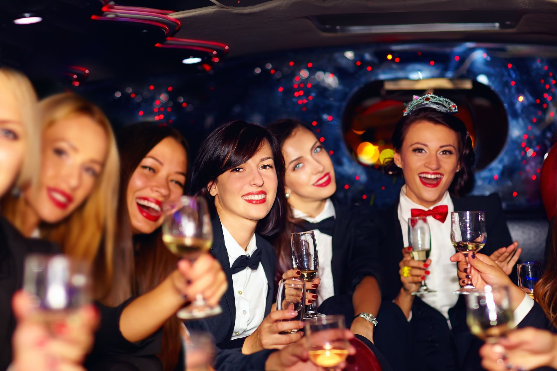 A group of women are toasting with champagne glasses in a limousine.