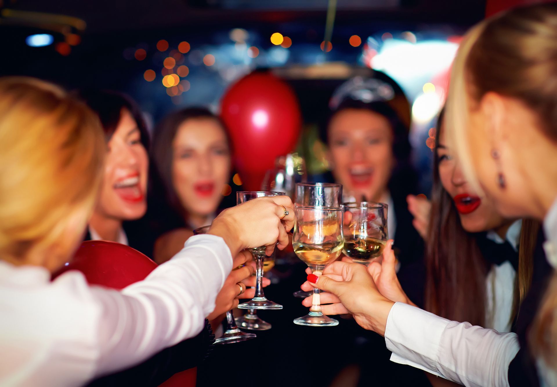 A group of women are toasting with wine glasses at a party.