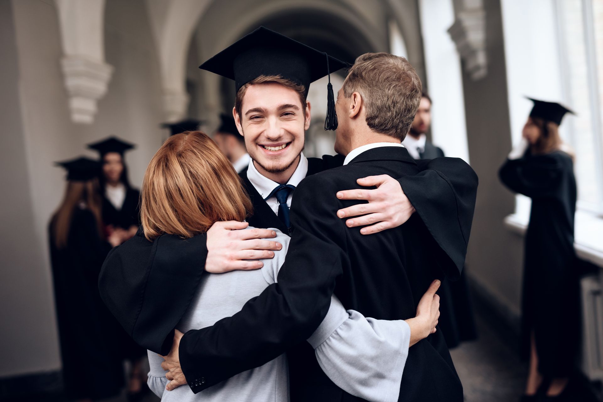 A group of graduates are hugging each other in a hallway.