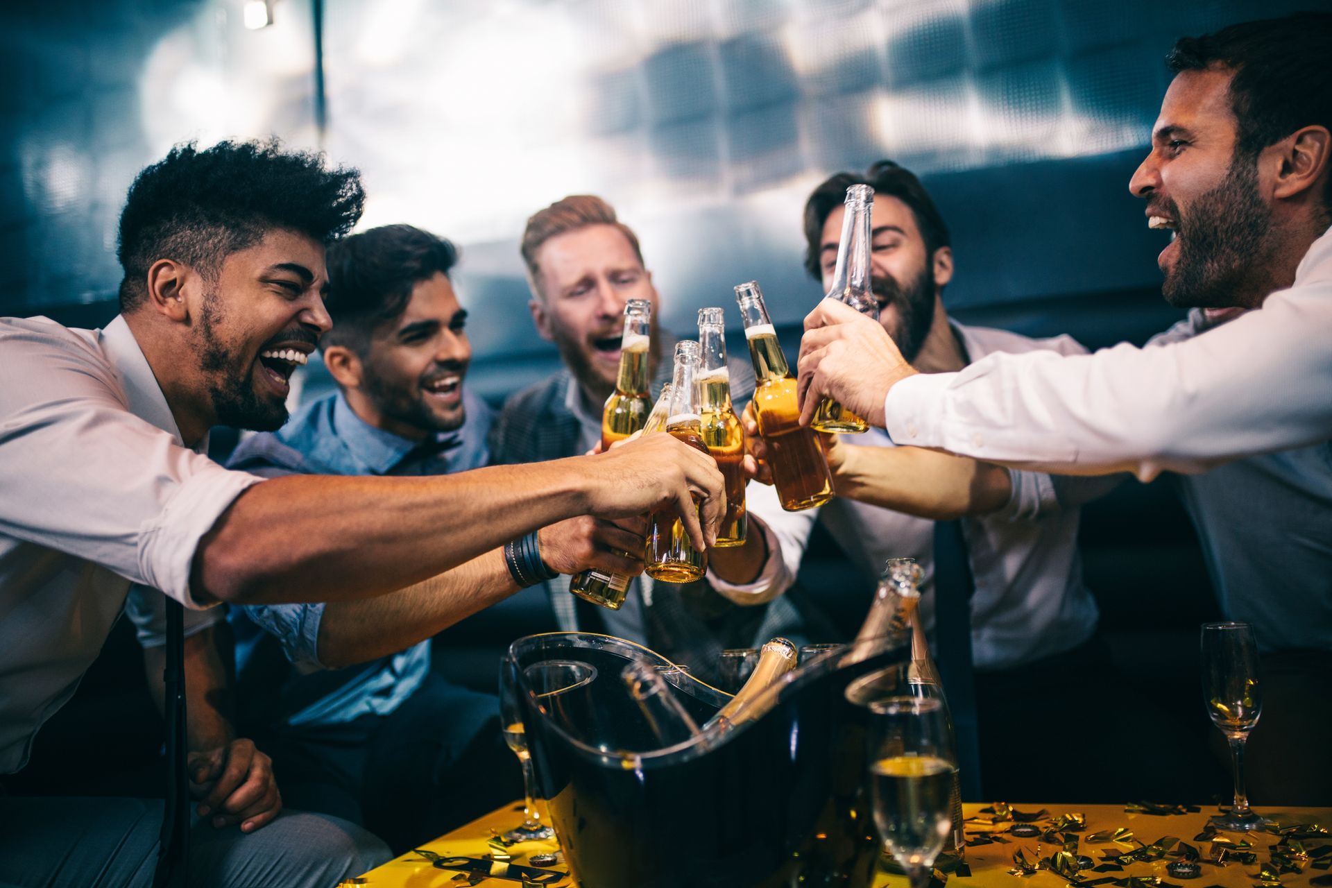 A group of men are toasting with beer and champagne at a party.