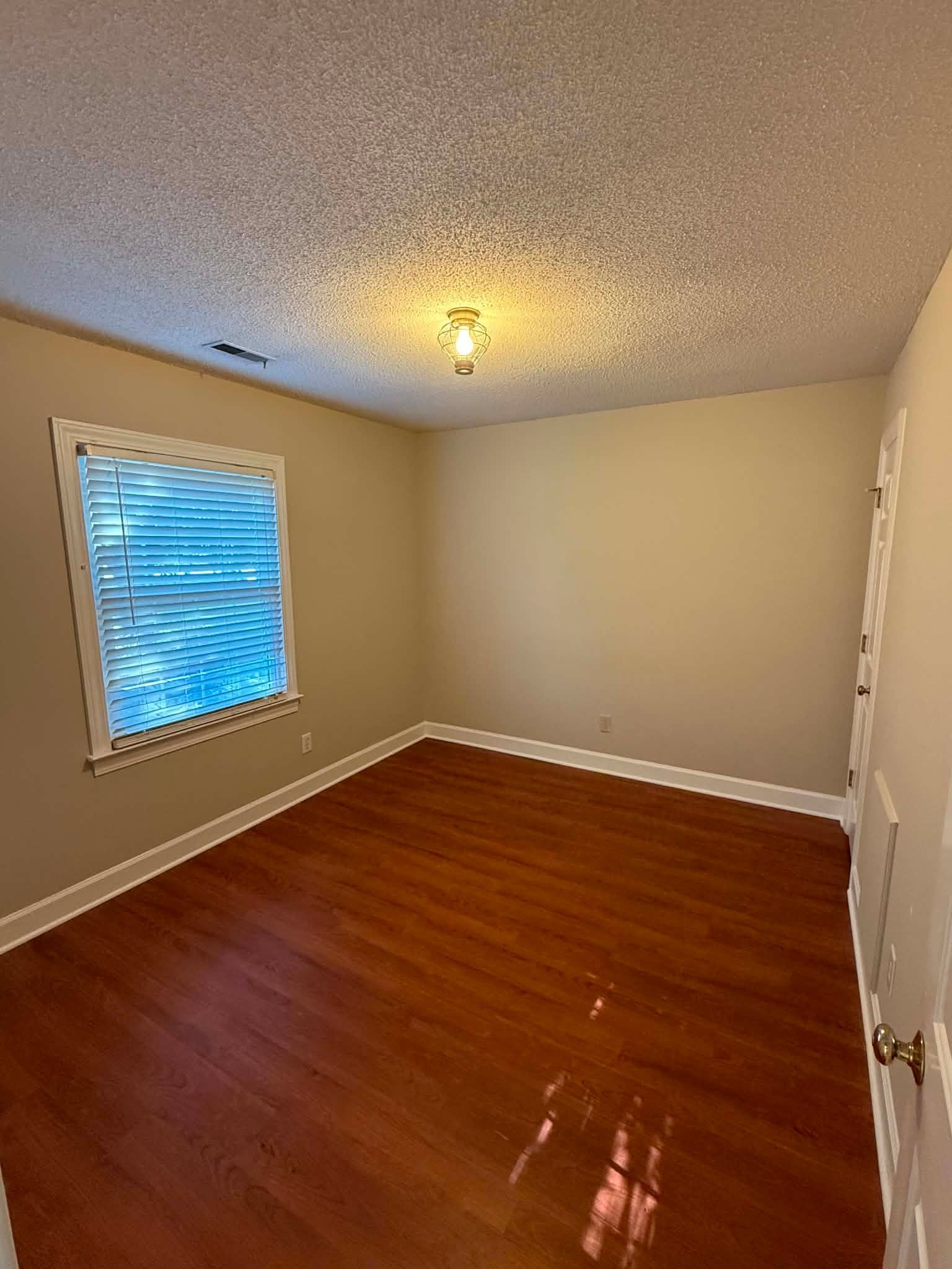 Bright white kitchen with wood floors, cabinets, and a glass door at the end of the room