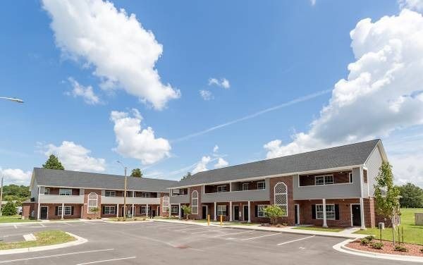 Two-story commercial buildings with brick and gray siding under a blue sky with fluffy clouds.