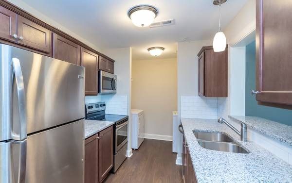 Kitchen with stainless steel appliances, dark cabinets, granite countertops, and wood floor.