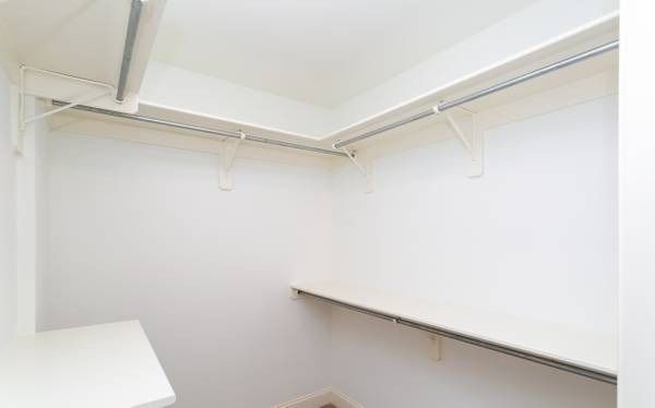 Empty white closet with shelving and a hanging rod.