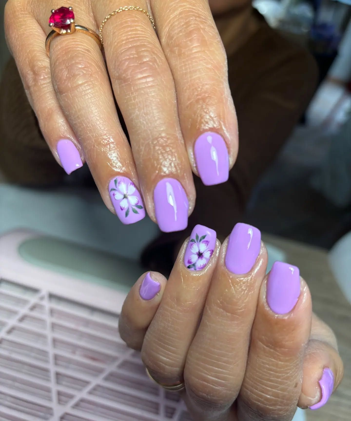 Le unghie di una donna sono dipinte di viola e hanno dei fiori.