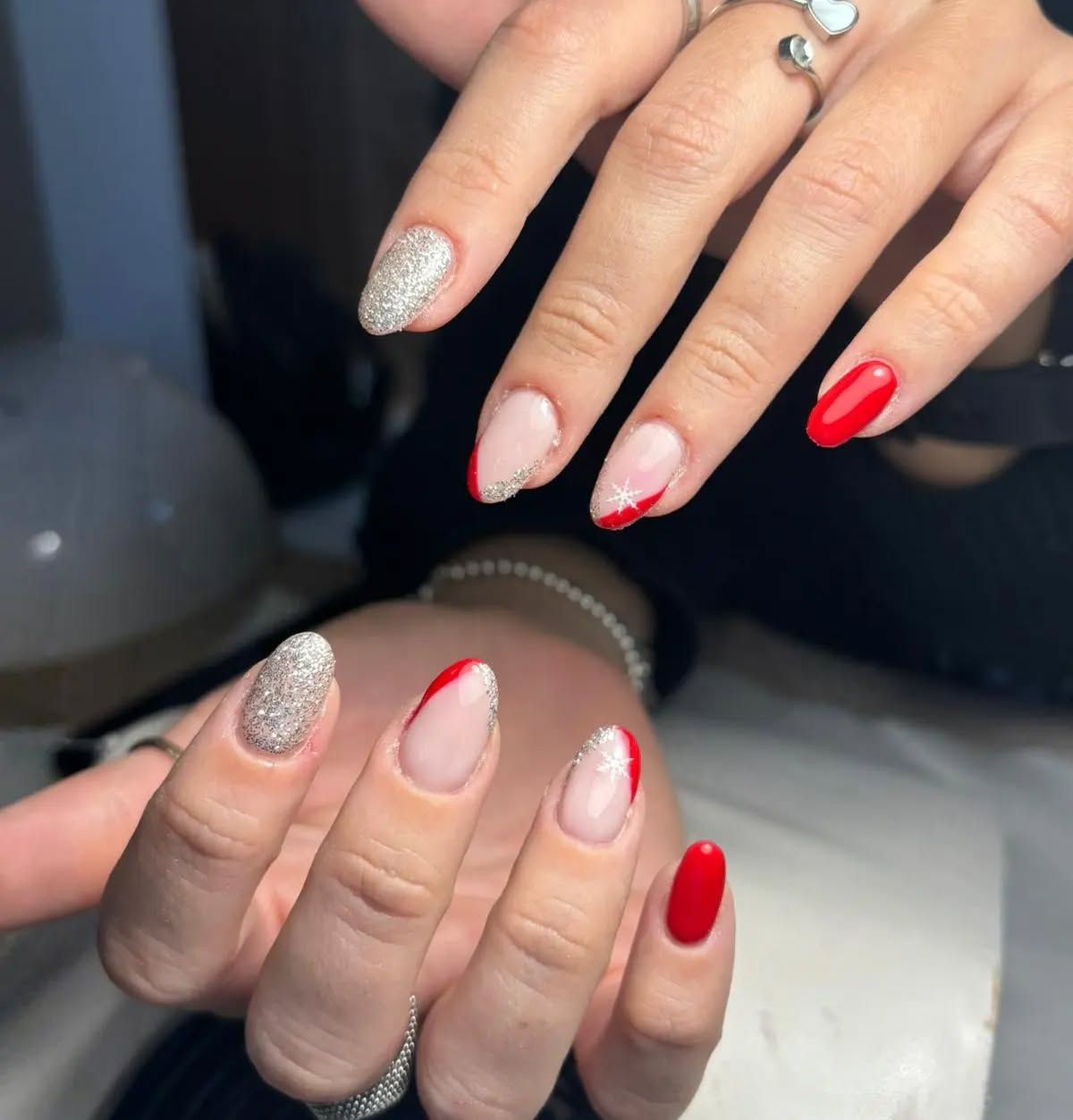 Un primo piano delle mani di una donna con unghie rosse e argentate