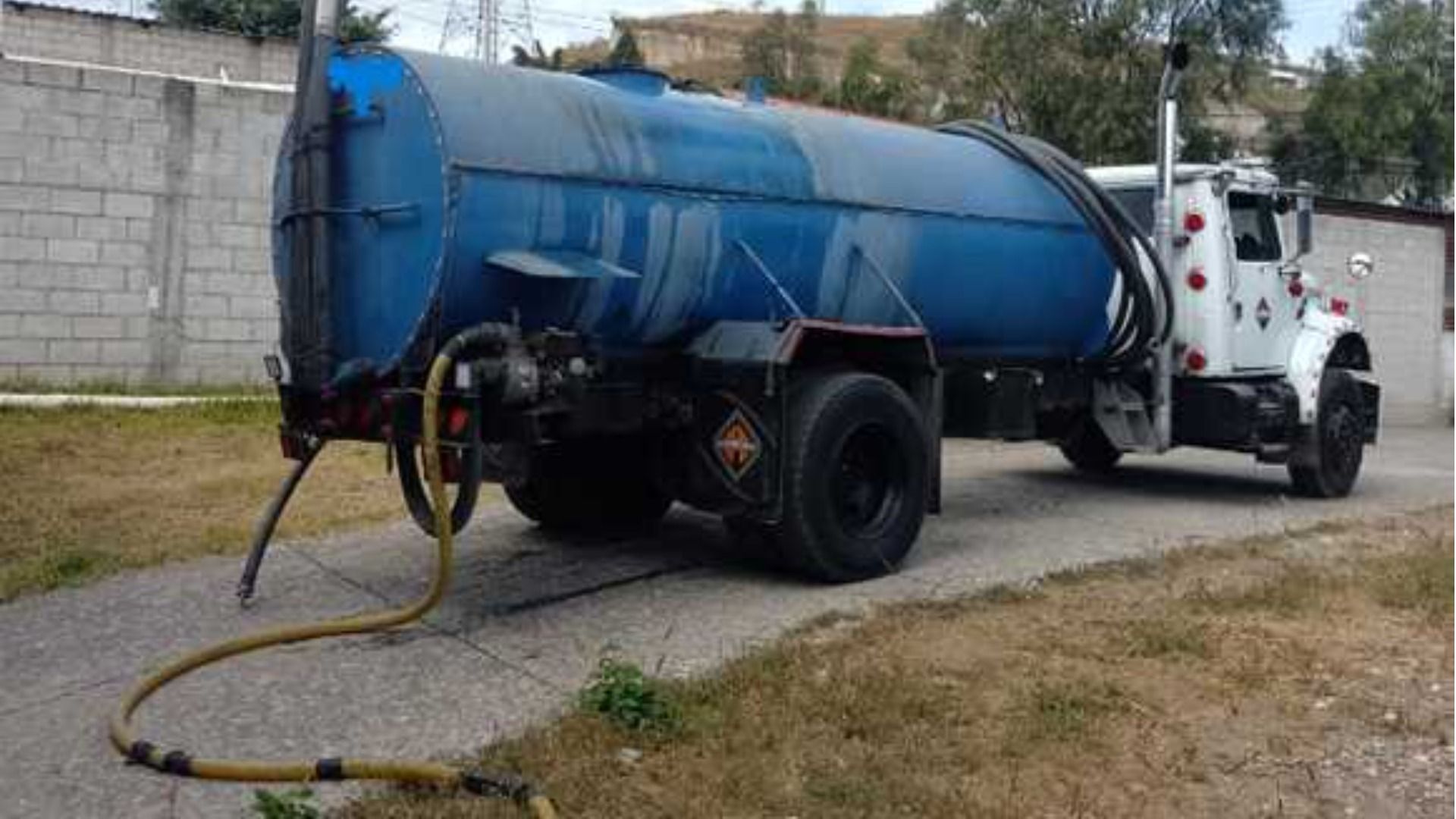 Un camión cisterna azul y blanco está estacionado al costado de la carretera.