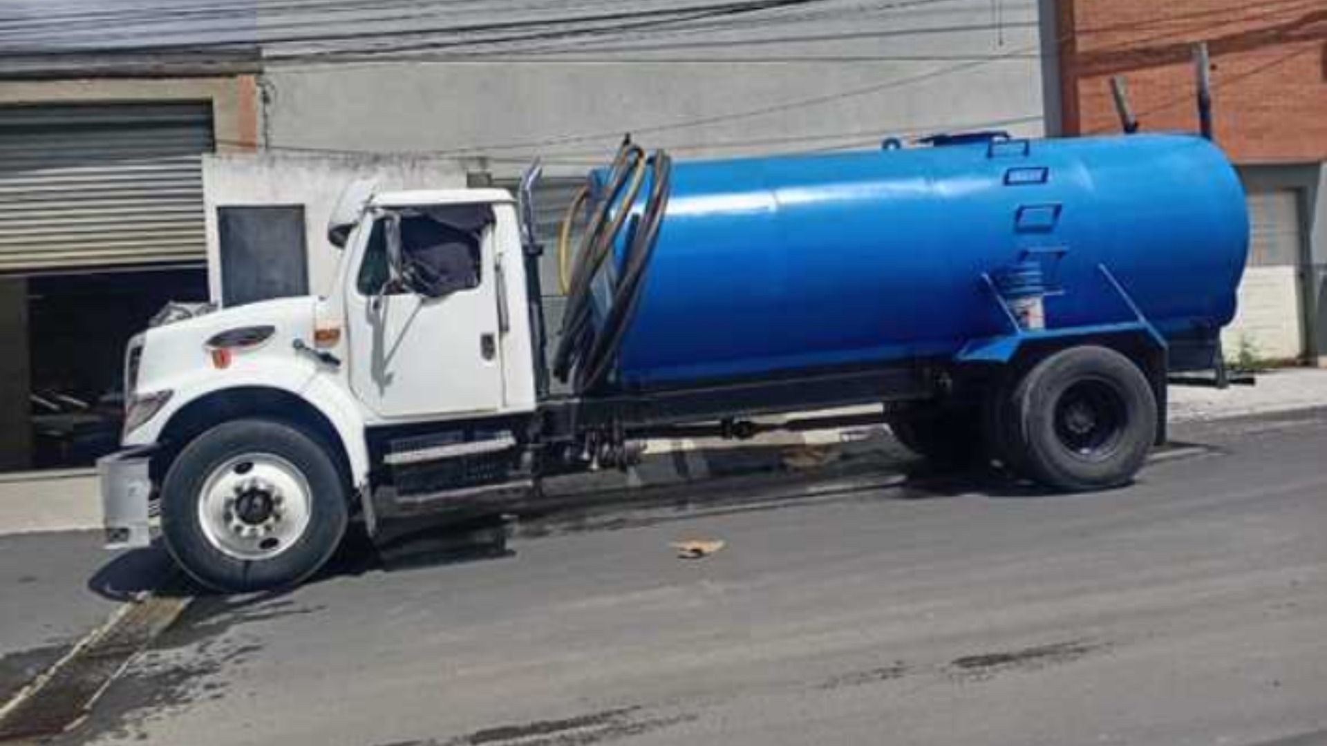 Un camión azul y blanco está estacionado al costado de la carretera.
