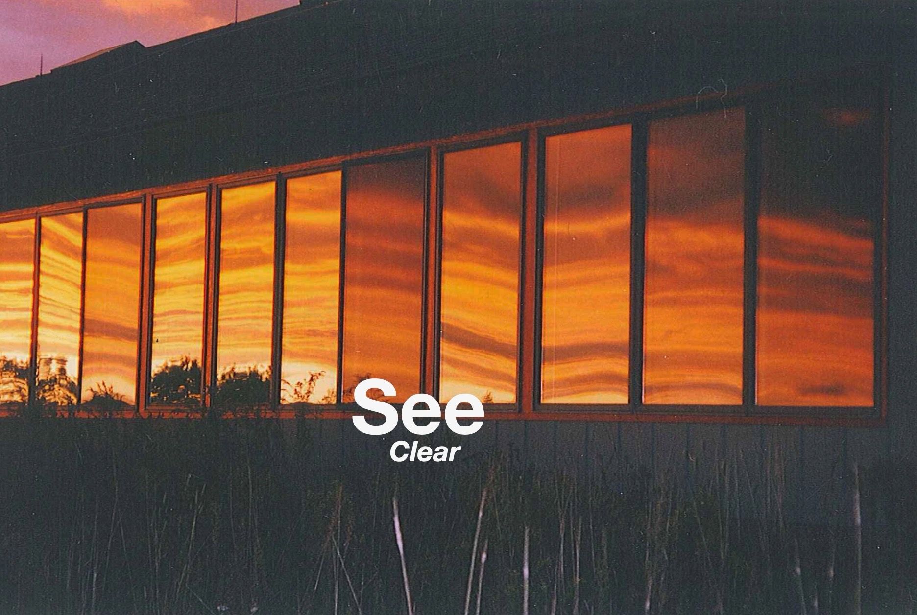 A row of windows reflects a vibrant orange sunset, with the text 