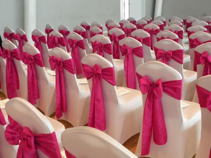 Rows of white chairs with bright pink bows arranged for a formal event