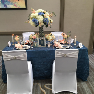 Elegant banquet table for two with blue and white floral centerpiece and place settings