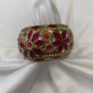 Red and gold jeweled decorative ring on white fabric backdrop