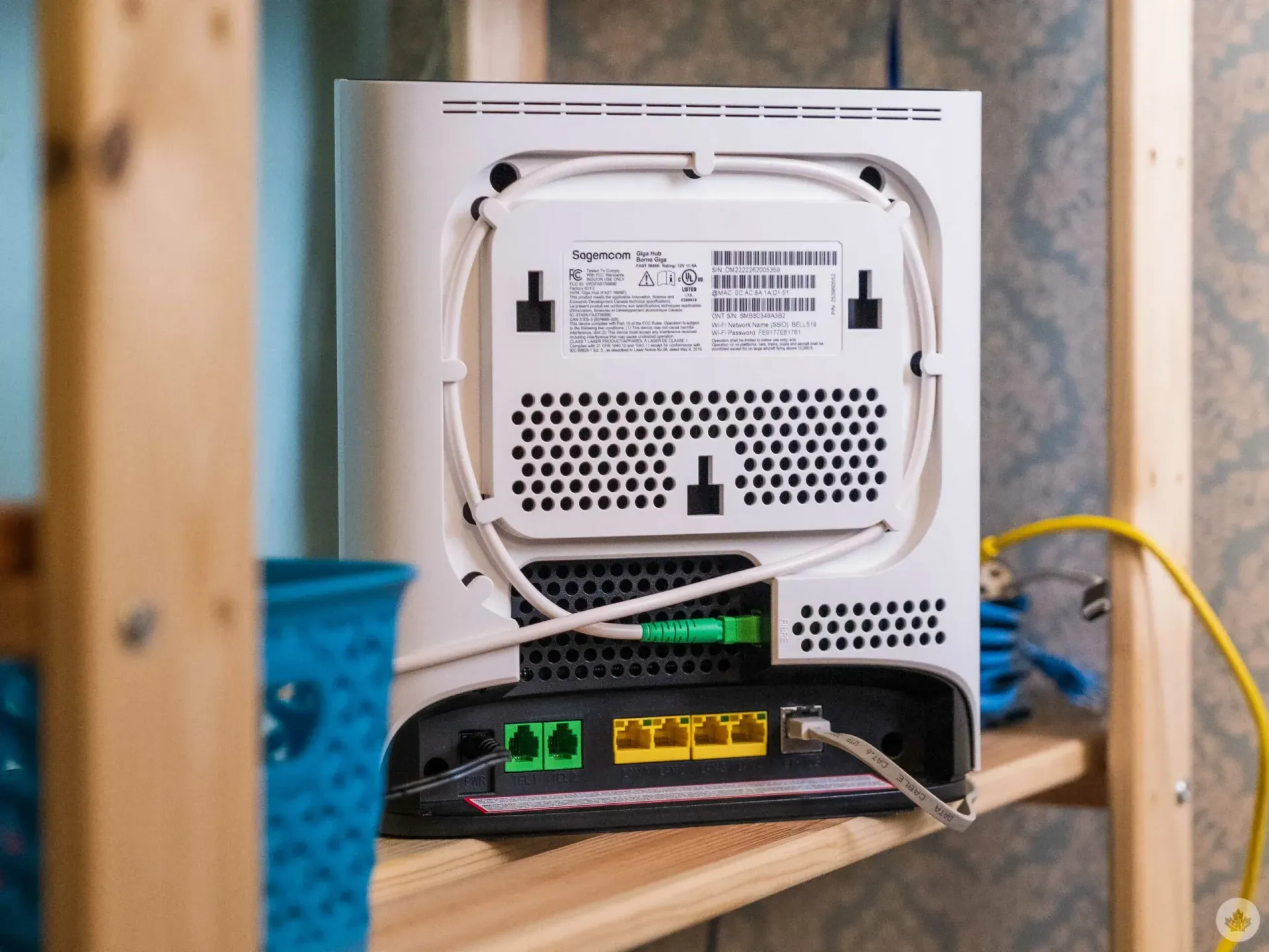 Two men installing a speaker on a white wall near a TV. One man is holding the speaker.