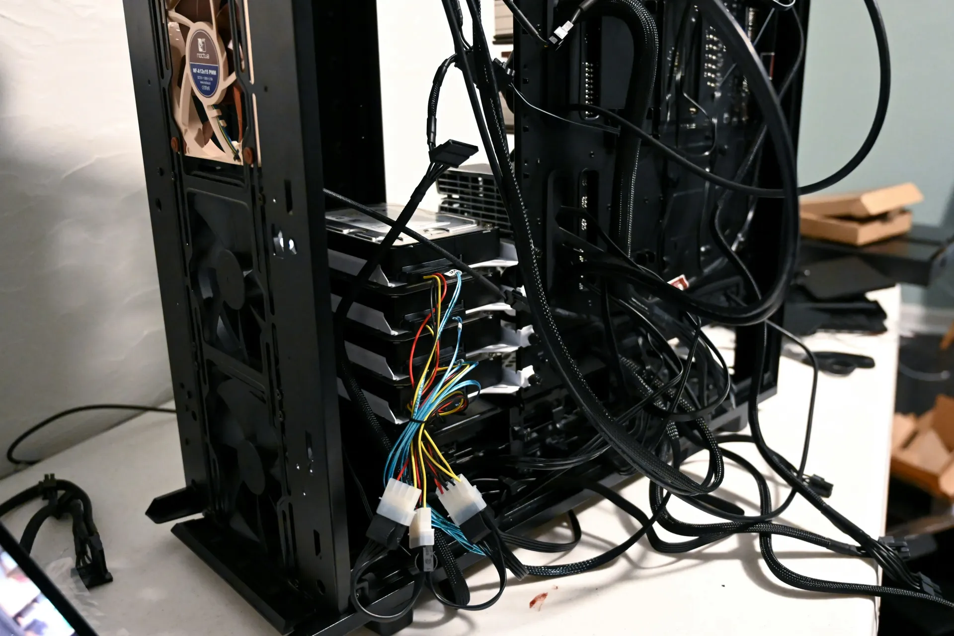 Black computer case with tangled wires, fans, and components on a white surface.