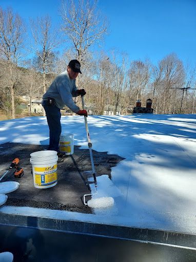 A man is painting a roof with a roller.