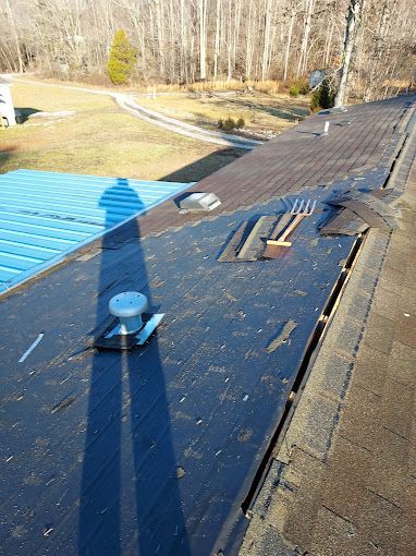 A roof with a fan on it and a shadow of a person on it.