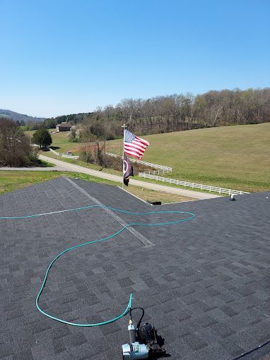 An american flag is flying on top of a roof next to a hose.