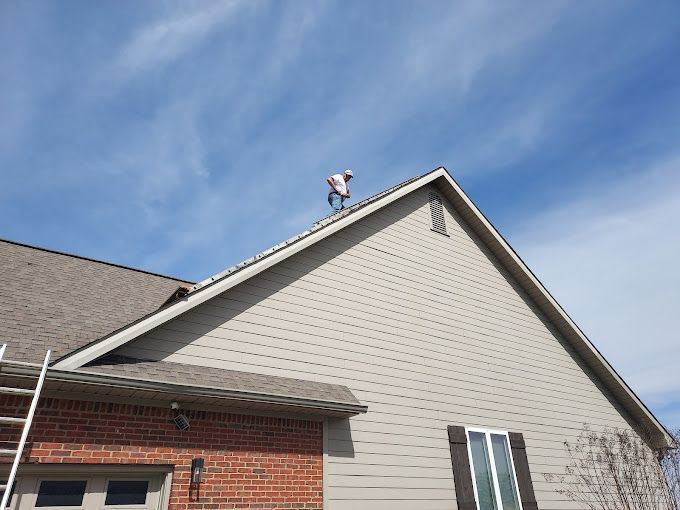 A man is standing on the roof of a house.