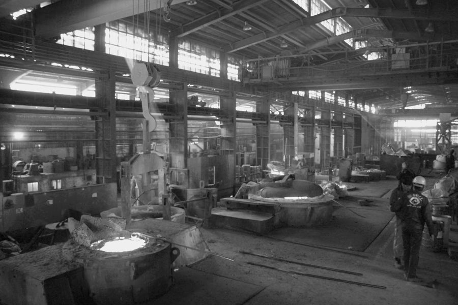 Ein Schwarzweissfoto einer Fabrik voller Schmelzöfen.