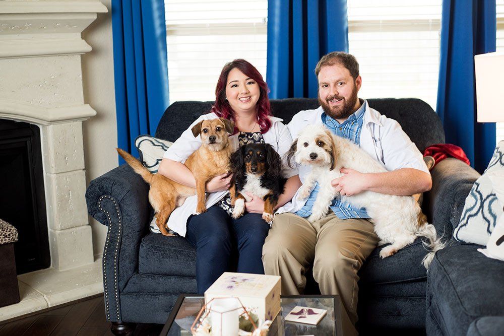 Both A Couple of Vets owners holding their dogs on a couch