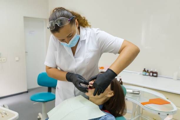 A dentist performs dentistry procedures to treat a woman's teeth and ensure optimal oral health.