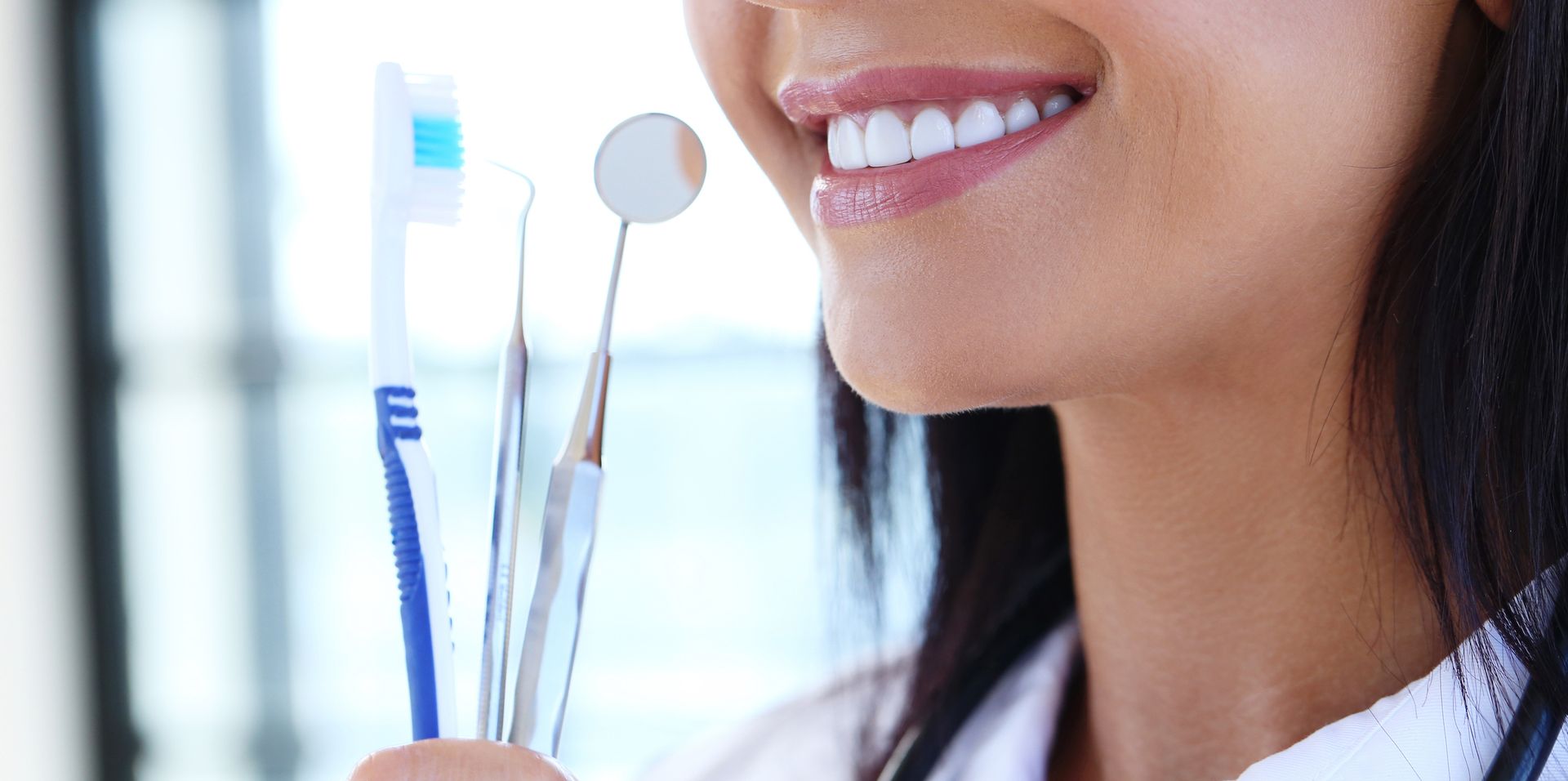 Close-up of a person holding a toothbrush and a mirror.
