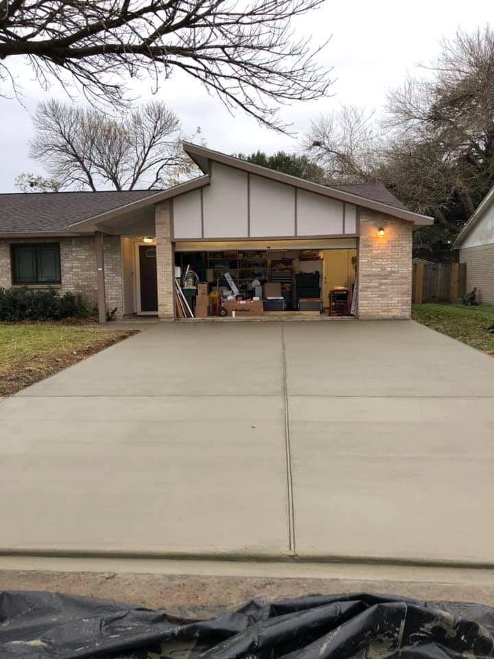 Suburban house with open garage and wide concrete driveway on a cloudy day