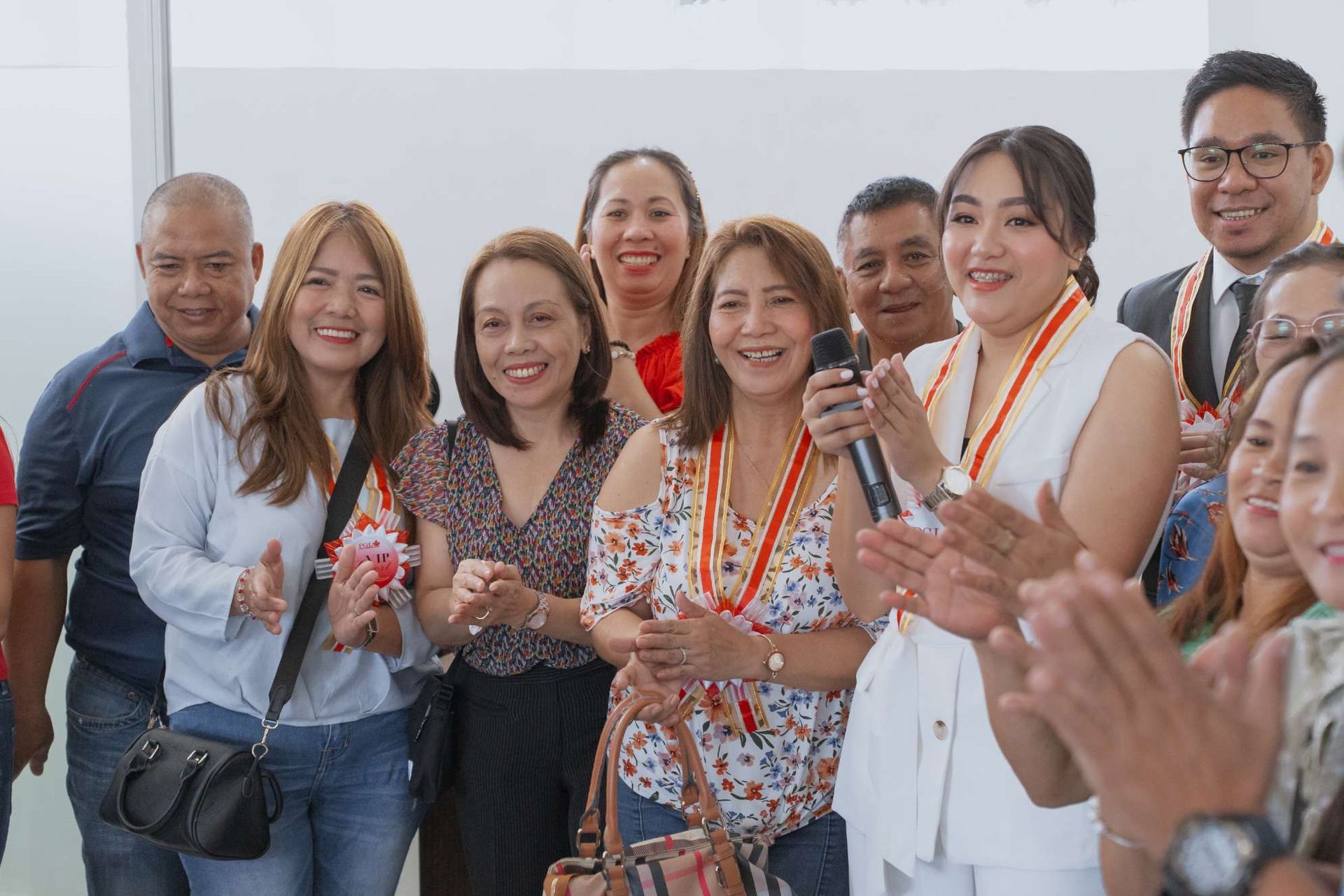 A group of people are posing for a picture while a woman holds a microphone.