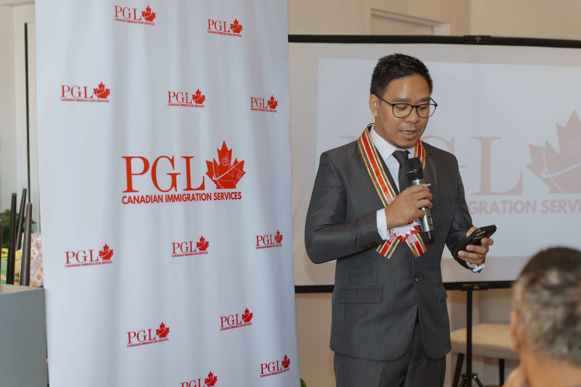 A man in a suit is speaking into a microphone while holding a cell phone.