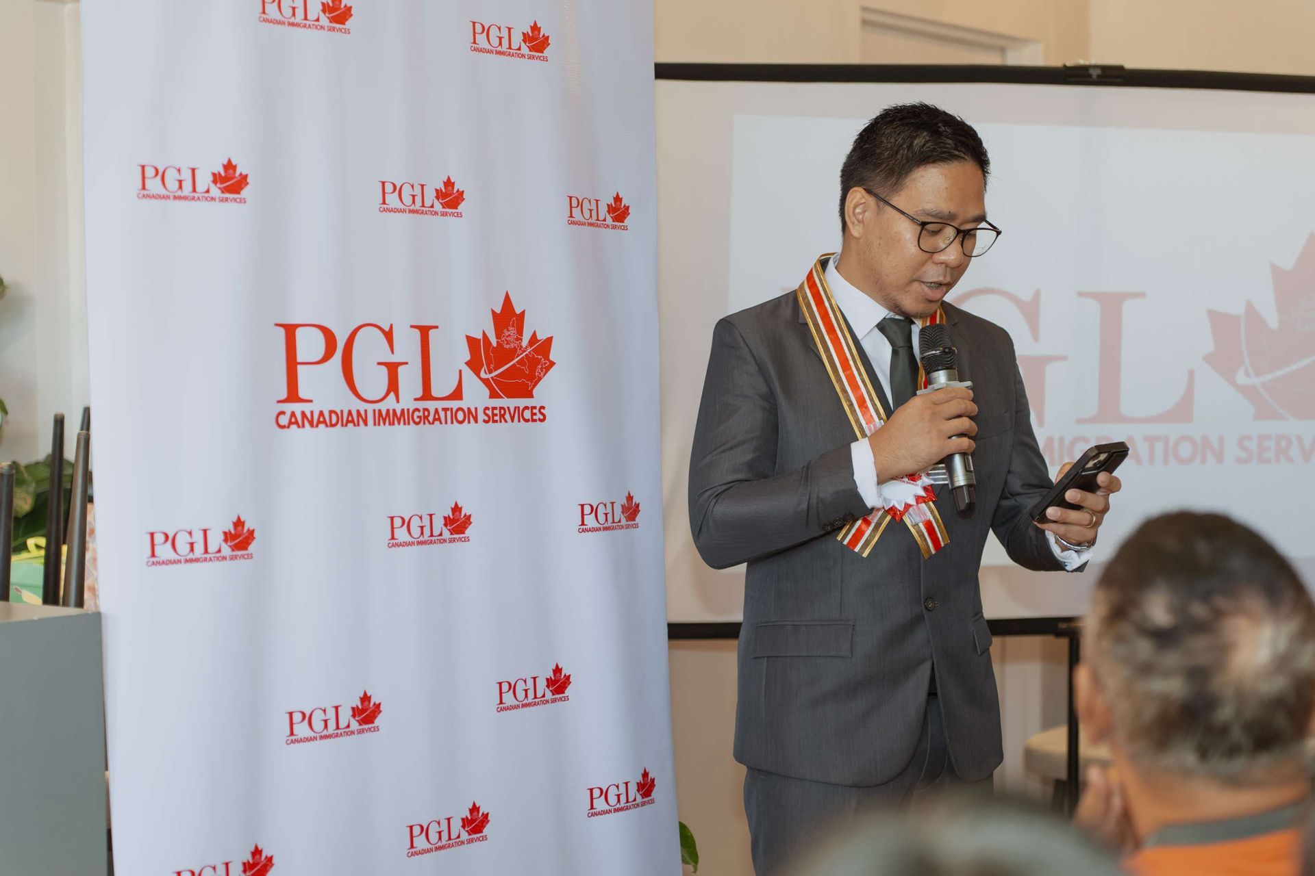 A man in a suit is speaking into a microphone while holding a cell phone.