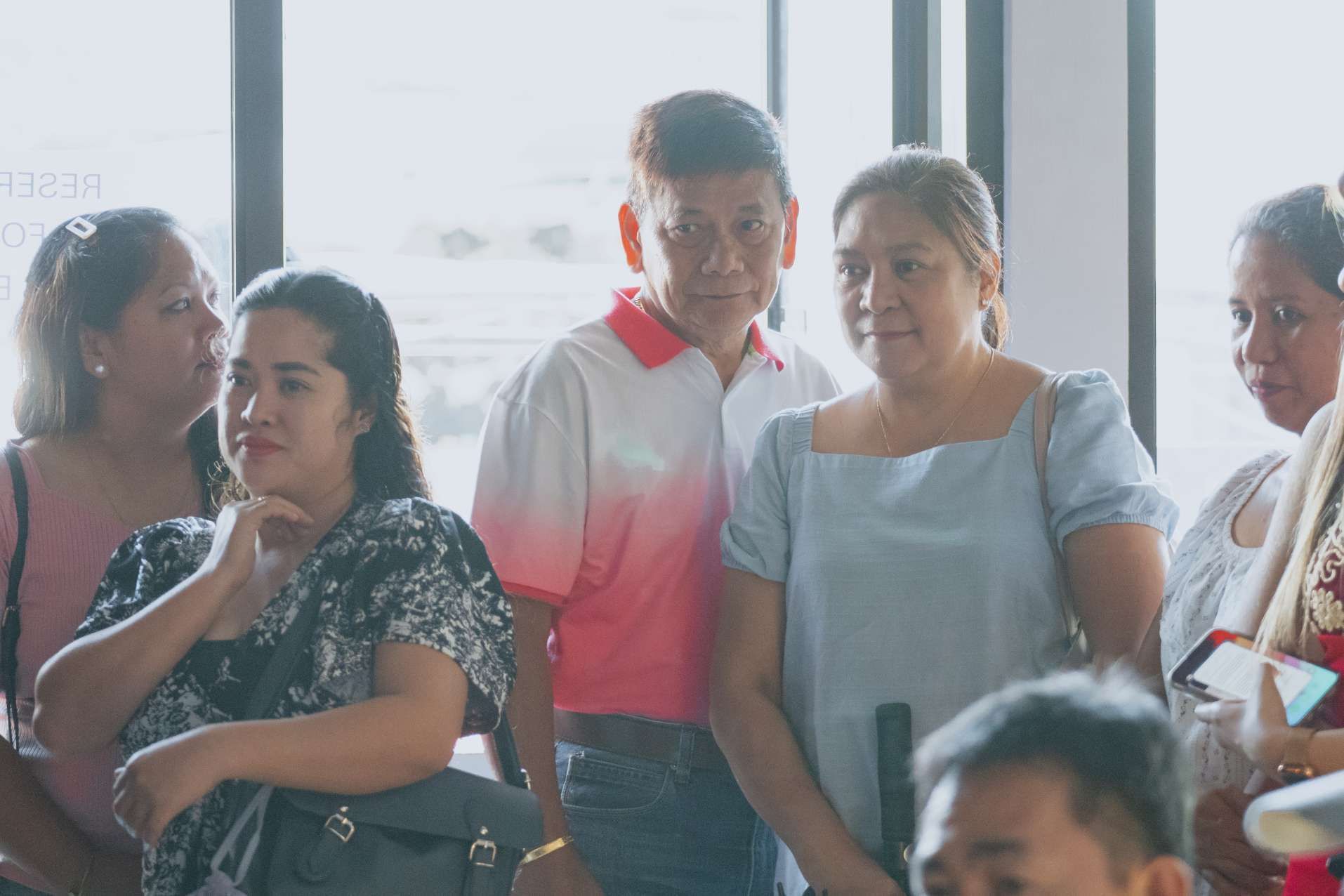 A group of people are standing in front of a window.
