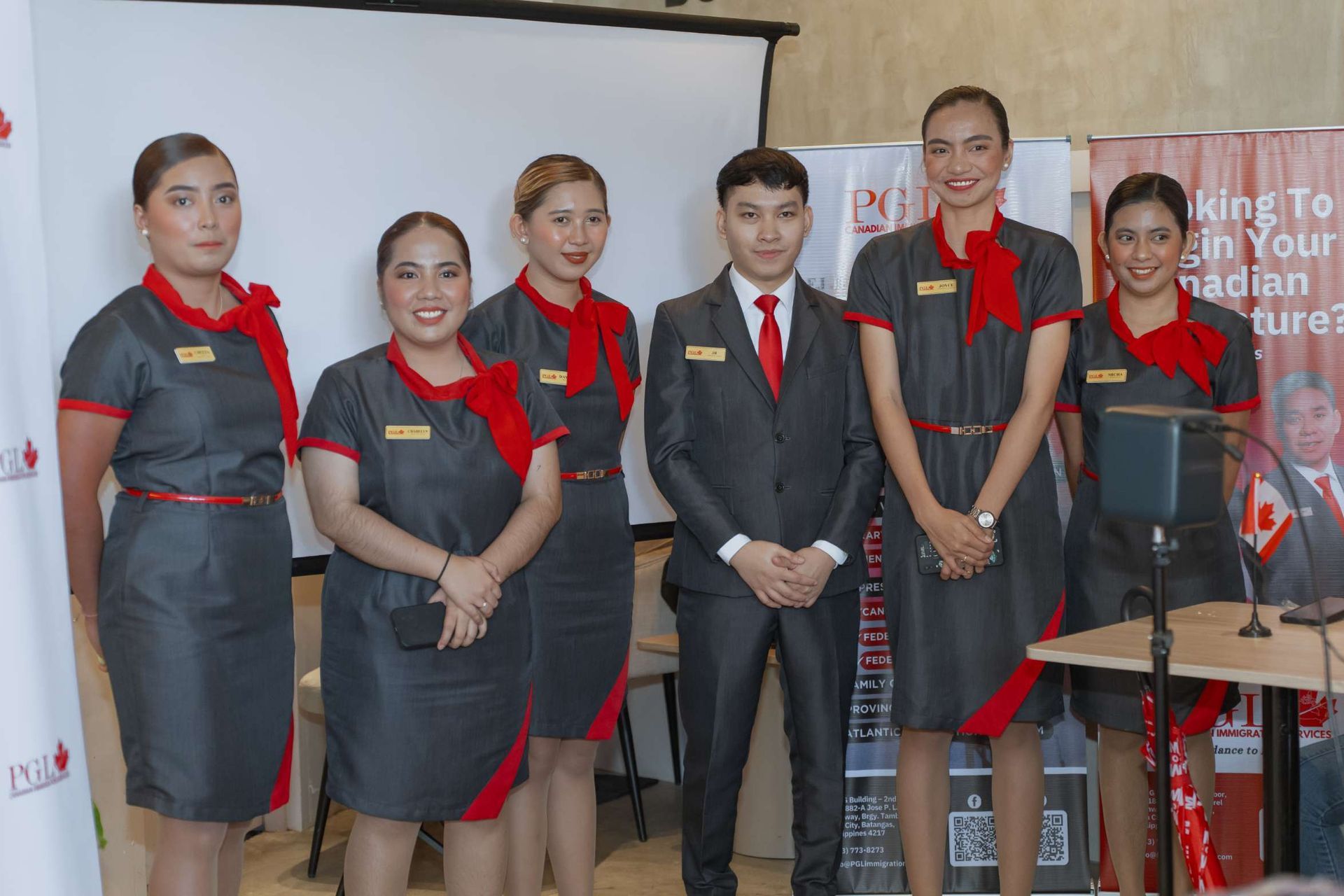 A group of people standing next to each other in front of a projector screen.