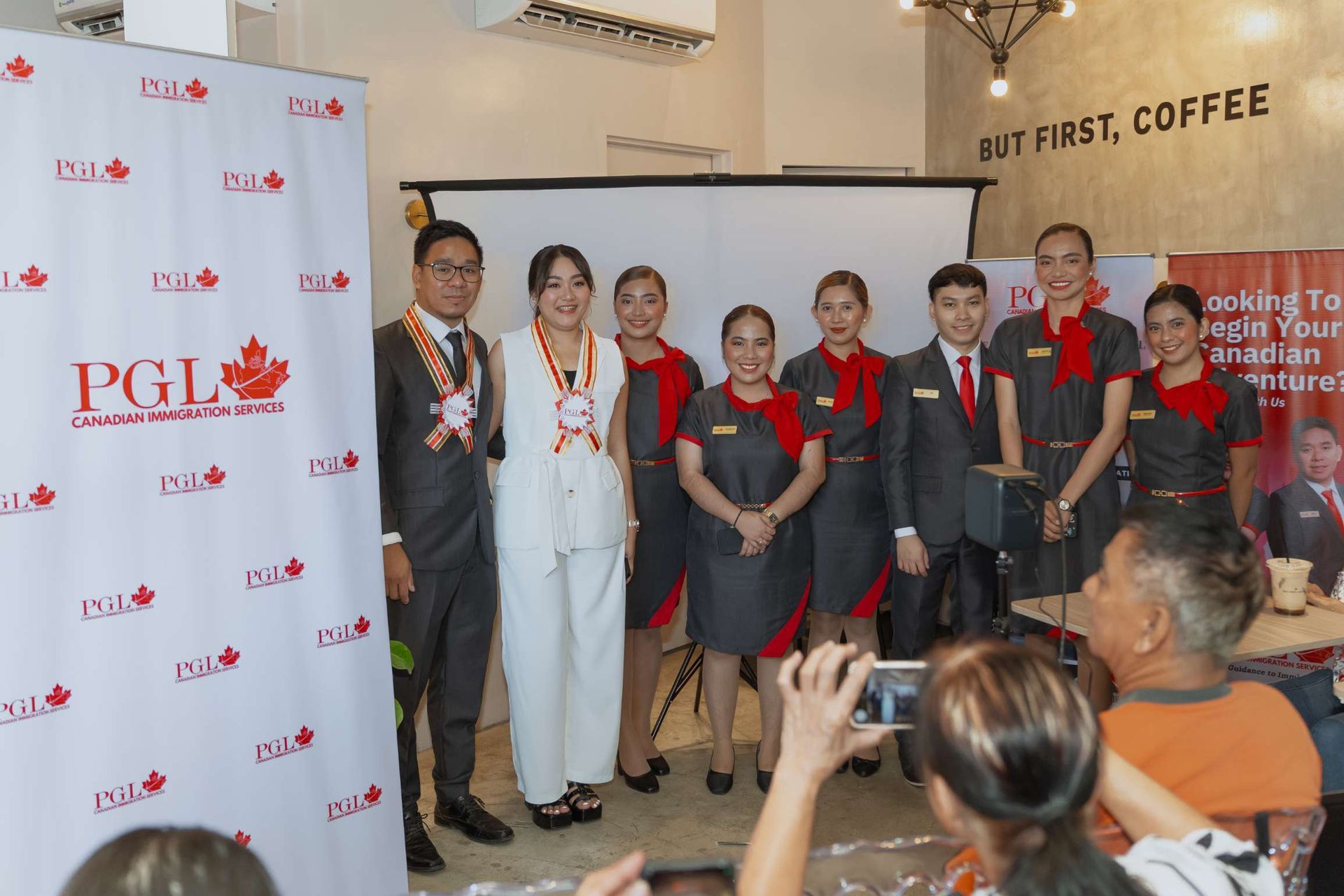 A group of people are posing for a picture in front of a pgi banner.