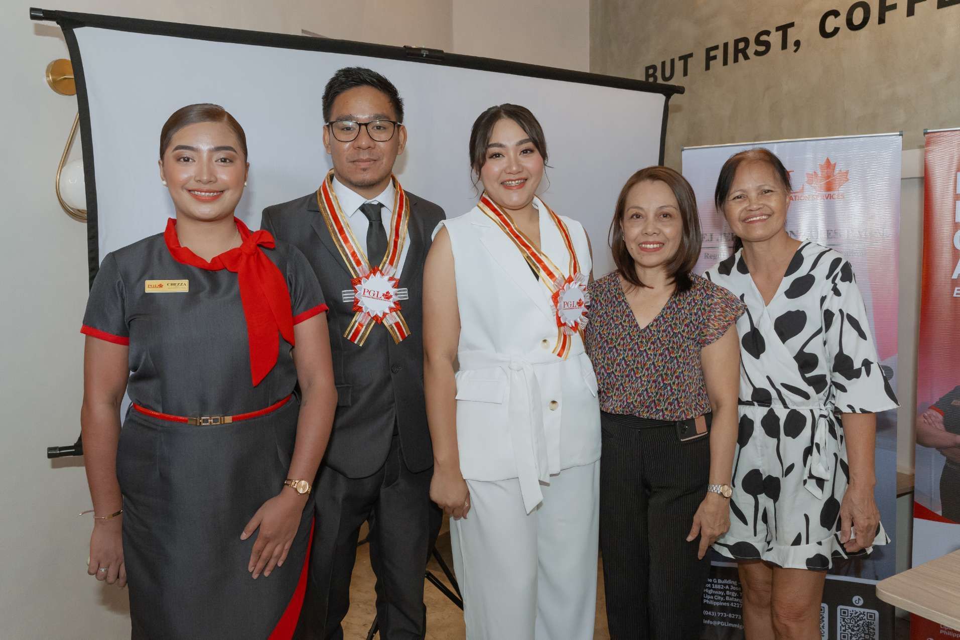A group of people are posing for a picture in front of a projector screen.