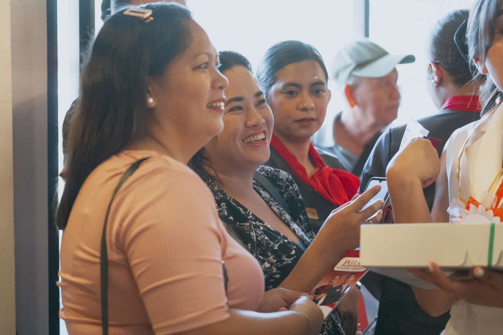 A group of women are standing in a line holding boxes and smiling.