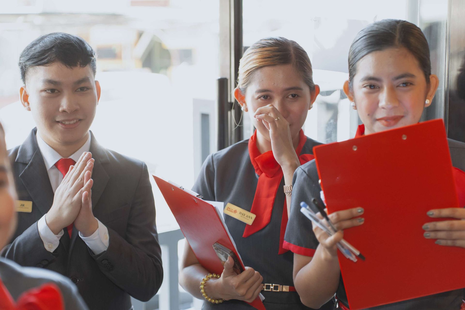 A group of people are standing next to each other holding red folders.