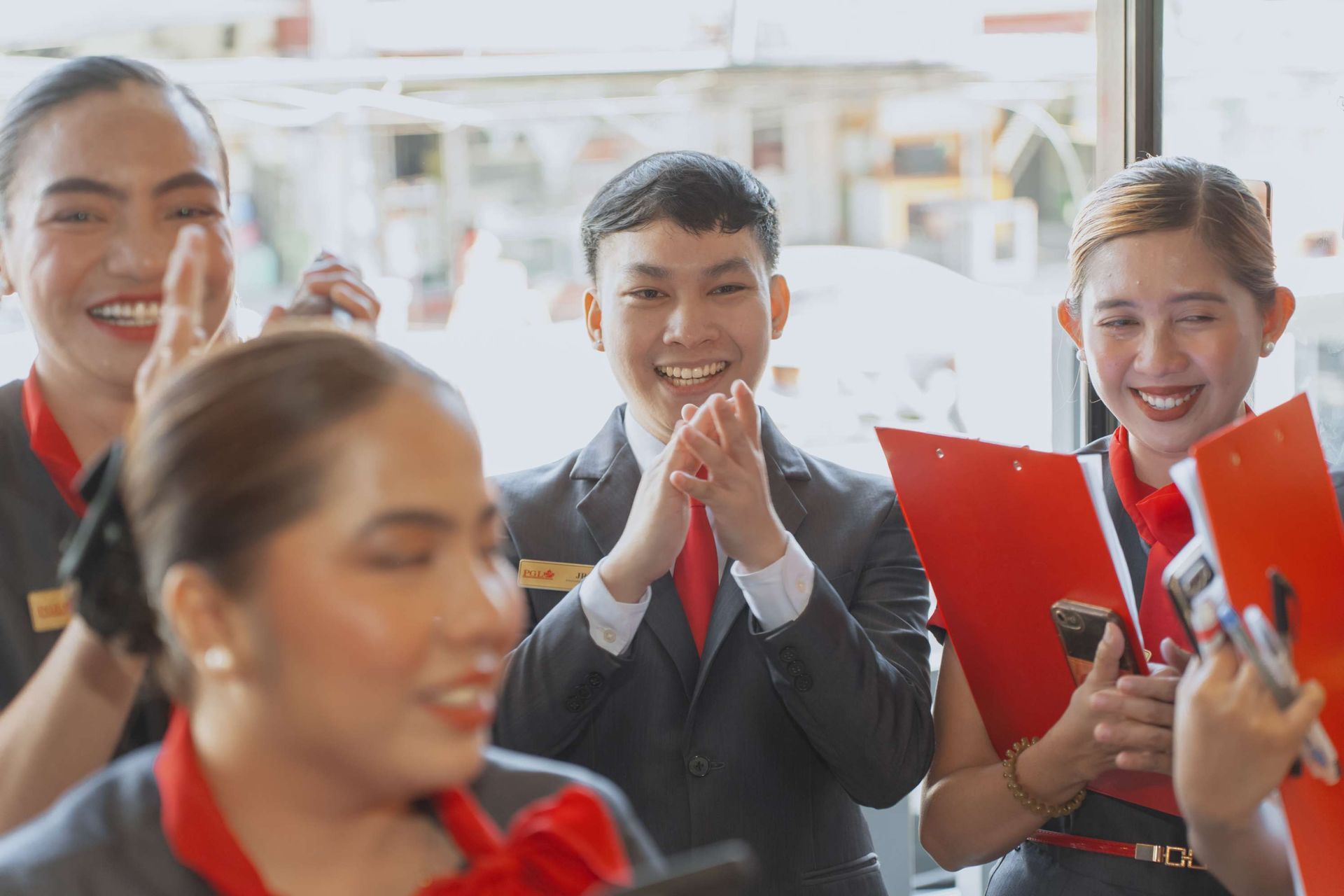 A group of people are clapping and smiling while holding folders.