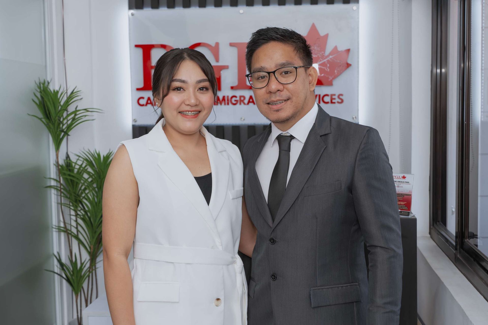 A man and a woman are posing for a picture in front of a sign.