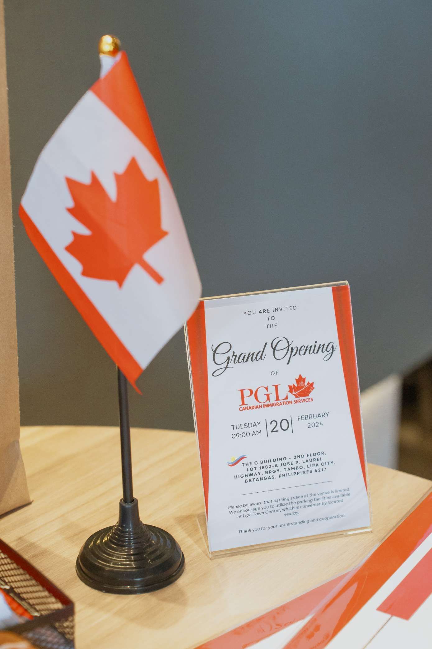 A small canadian flag is on a table next to a sign that says grand opening