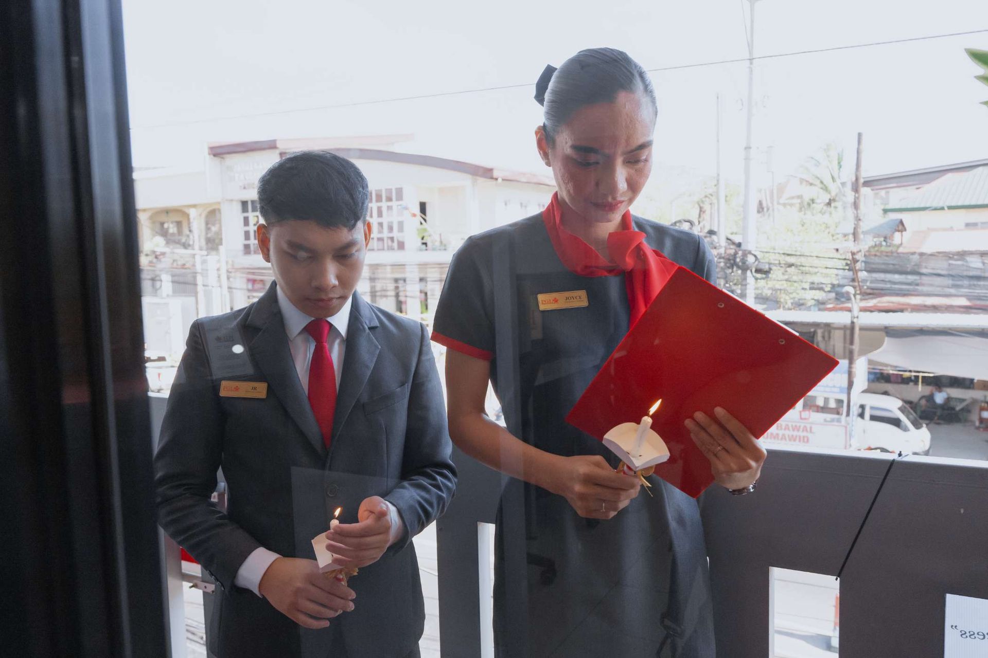 A man and a woman are standing on a balcony looking at a clipboard.