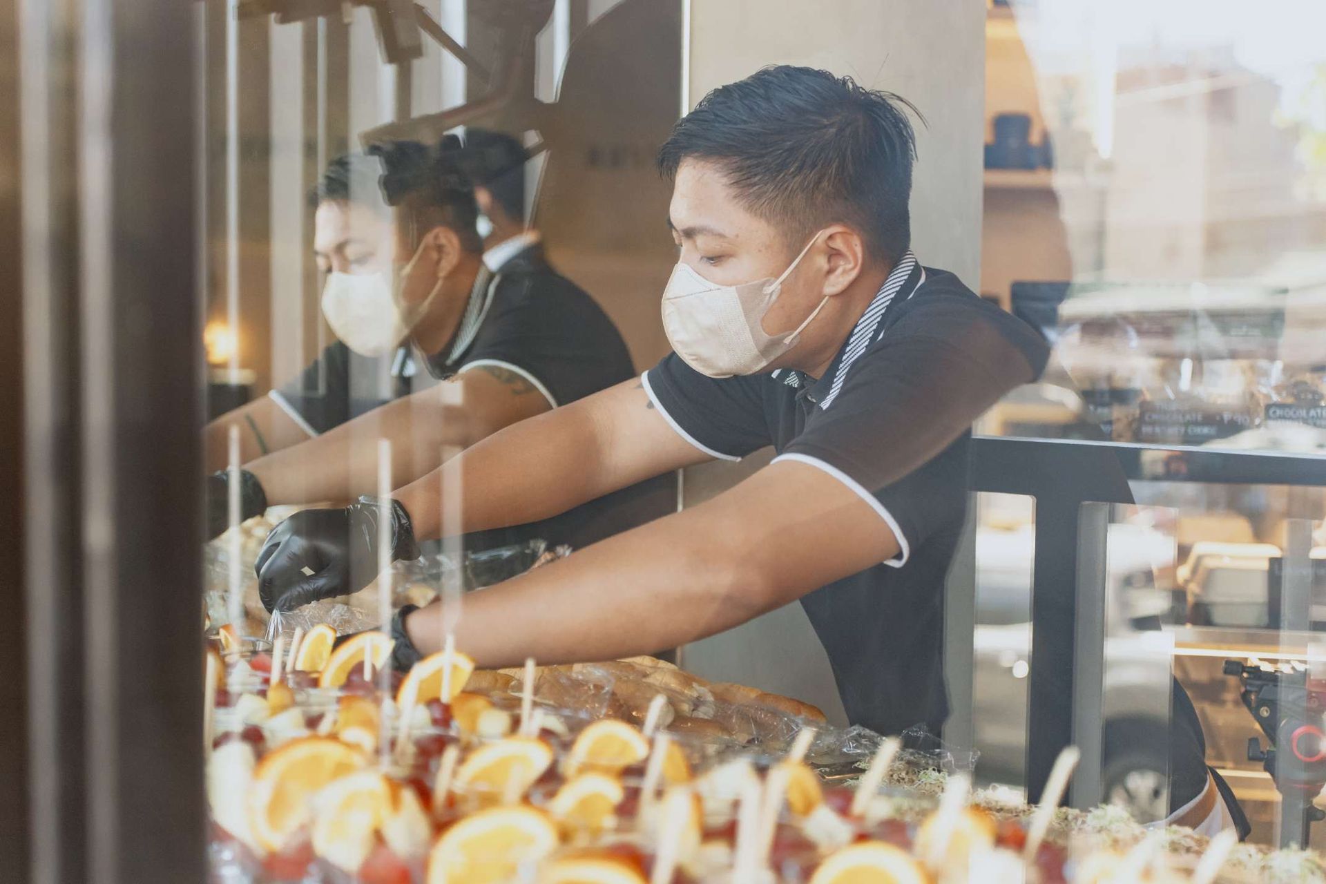 A man wearing a mask is preparing food in a restaurant.